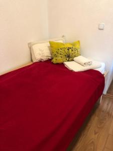 a bed with a red blanket and pillows on it at Haus am Wald in Hohndorf