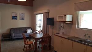 a kitchen and living room with a table and a microwave at Billungar Unit 1 at Hat Head - 1 Creek Street in Hat Head