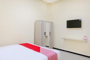 a white room with a bed and a tv at SUPER OYO 1468 SM House in Malang