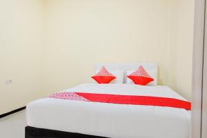 a bed with red and white sheets and pillows at SUPER OYO 1468 SM House in Malang