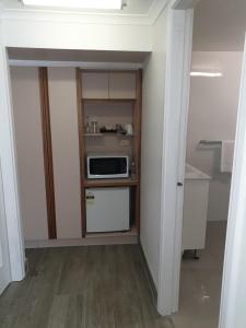 a small kitchen with a microwave on a shelf at Forstay Motel in Forster