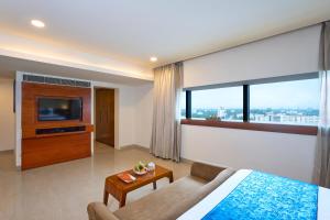 a bedroom with a bed and a tv and a couch at The Raviz Calicut in Kozhikode