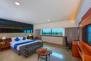 Habitación de hotel con cama y TV de pantalla plana. en The Raviz Calicut en Kozhikode