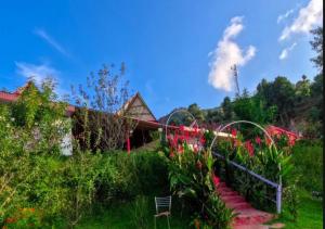 a garden with red flowers and a house at Haut Monde King's Paradise Resort in Kanatal