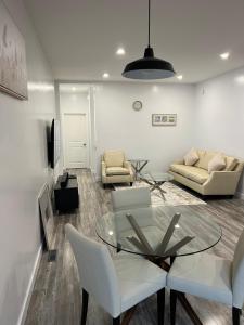 a living room with a glass table and white chairs at Panel Apartment in Winnipeg