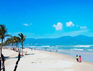 a group of people on a beach with palm trees at Phú An Hotel in Da Nang