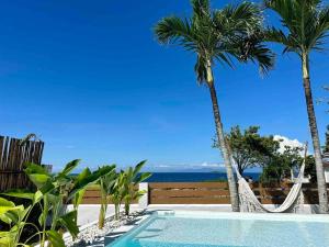 a swimming pool with two palm trees and a hammock at Pawikan Seaview Villa with breakfast in Moalboal