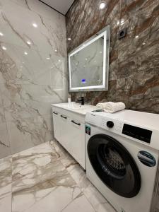 - un lave-linge dans la salle de bains pourvue d'un lavabo dans l'établissement Aportament in Abyroy Residence, à Atyraū