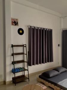 um quarto com uma cama, uma prateleira e uma janela em The Vinyl Homestay em Ho Chi Minh