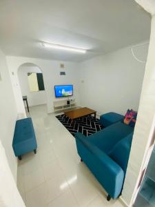 a living room with a blue couch and a tv at Simple2 Guesthouse in Pantai Cenang