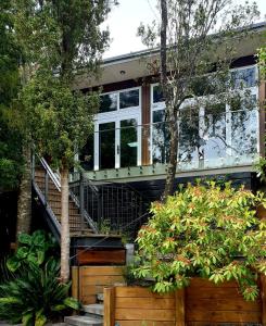 a house with a staircase and trees in front of it at Torbay Tree Tops in Auckland