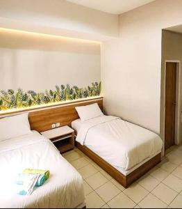 2 łóżka w pokoju hotelowym w obiekcie Caniga Hotel Yogyakarta w mieście Gondowulung