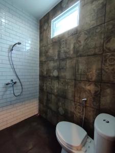 a bathroom with a toilet and a window at Caniga Hotel Yogyakarta in Gondowulung