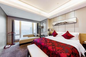 Shenzhen LANGYUE International Hotel في Longgang: غرفة نوم كبيرة مع سرير احمر واريكة