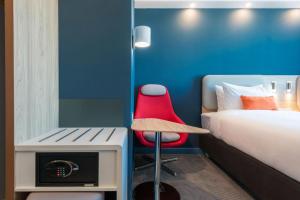 Cette chambre comprend un lit et une chaise rouge. dans l'établissement Holiday Inn Express - Astana - Turan, an IHG Hotel, à Astana