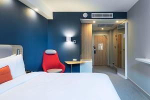 um quarto de hotel com uma cama e uma cadeira vermelha em Holiday Inn Express - Astana - Turan, an IHG Hotel em Astana