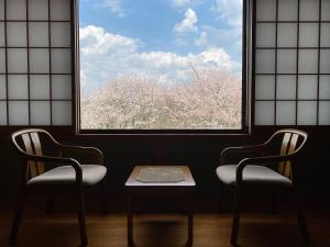 2 sillas y una mesa frente a una ventana en 吉野荘湯川屋 Yoshinosou Yukawaya, en Yoshino
