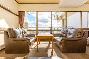 two leather chairs and a table in a room with windows at Ooedo Onsen Monogatari Minoh Kanko Hotel in Minoo