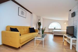 a living room with a yellow couch and a television at FV/ Mariacka 7 - Studio apartment -Katowice in Katowice