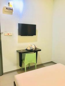 a room with a desk with a green chair and a tv at Kozi Hotel - Bukit Indah in Johor Bahru