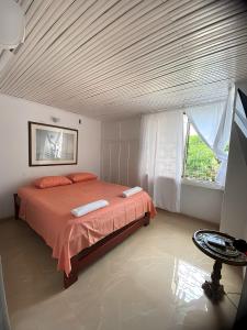 ein Schlafzimmer mit einem Bett mit orangefarbener Bettwäsche und einem Fenster in der Unterkunft Casa Los Almendros, Valledupar casa completa in Valledupar