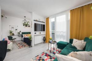 een woonkamer met een groene bank en een tv bij Specious City Center Studio with Park View by ECRU WWA23 in Warschau