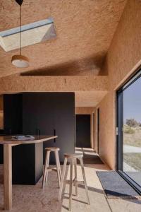 a kitchen with two stools and a table in a room at Common Kosci - luxury bespoke cabin in the Snowies in Jindabyne