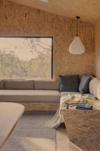 a living room with a couch and a window at Common Kosci - luxury bespoke cabin in the Snowies in Jindabyne