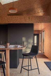 a kitchen with a table and a black chair at Common Kosci - luxury bespoke cabin in the Snowies in Jindabyne