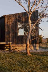 a building with a tree in front of it at Common Kosci - luxury bespoke cabin in the Snowies in Jindabyne