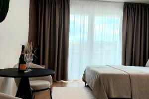 a bedroom with a bed and a table with a bottle of wine at Apartmán SoHo s private garage parking free, 5 min peso do centra in Košice