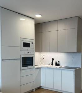 uma cozinha com armários brancos, um lavatório e um micro-ondas em Apartmán SoHo s private parking, 5 min peso do centra em Košice