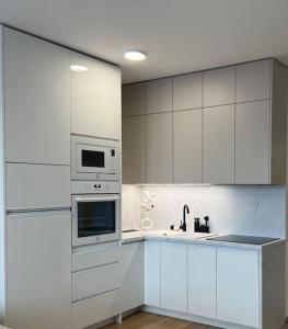a kitchen with white cabinets and a sink and a microwave at Apartmán SoHo s private garage parking free, 5 min peso do centra in Košice