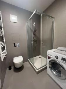 y baño con ducha y lavadora. en Apartmán SoHo s private parking, 5 min peso do centra, en Košice