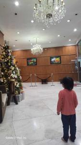 un jeune enfant jouant à un jeu vidéo dans une salle avec un sapin de Noël dans l'établissement MNK Condo Transient - Albergo Residences, à Baguio