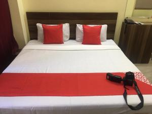 una macchina fotografica seduta su un letto con cuscini rossi di Arora classic guest house ad Amritsar