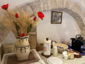 a vase with red flowers sitting on a table at Trullo Delle Sorelle in Alberobello