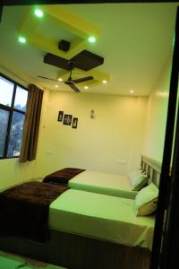 a bedroom with two beds and a ceiling fan at HOTEL AKSHAYAM GRAND INN in Yelagiri