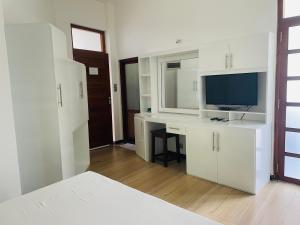 a room with a desk with a computer and a television at White House Hotel Mirissa in Mirissa