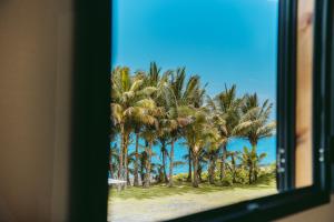 サン・ブノワにあるL'Auberge Créoleのヤシの木が茂るビーチの景色を望む窓