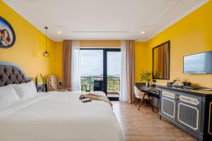 a hotel room with a bed and a desk and a television at Athenia Hoi An Boutique Hotel & Spa in Hoi An