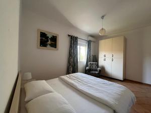 1 dormitorio con 1 cama blanca grande y 1 silla en Vivo Apartment en Durrës