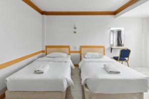 two beds in a room with a blue chair at Phu Inn Hotel in Khon Kaen