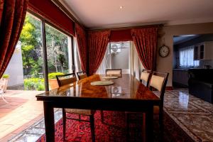 uma sala de jantar com uma mesa de madeira e uma grande janela em Royal Ridge Guesthouse em Pretoria