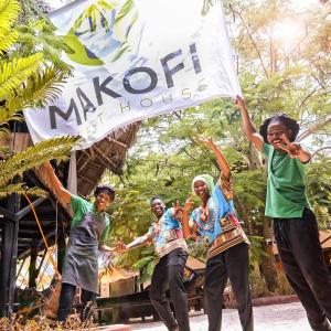 a group of people holding a sign in front of a building at Makofi Guest House in Nungwi