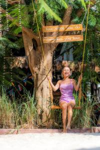 a woman sitting on a swing next to a tree at Makofi Guest House in Nungwi