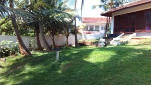 un patio con palmeras y una casa en Absolute Breeze by cherins, en Matara