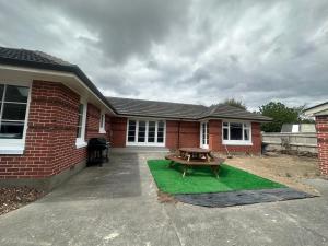 a patio with a picnic table in front of a house at Sunny House with 5 Bedrooms(near airport) in Christchurch