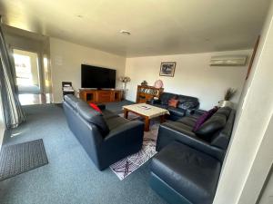 ein Wohnzimmer mit Sofas und einem Flachbild-TV in der Unterkunft Sunny House with 5 Bedrooms(near airport) in Christchurch