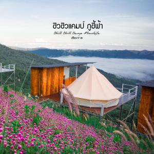 a tent on top of a hill with pink flowers at ชิวชิวแคมป์ ภูชี้ฟ้า in Ban Huai Han